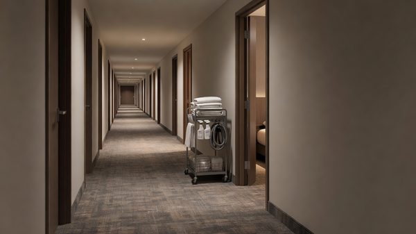 Hotel housekeeper's cart parked in a quiet guest-floor corridor with doors along both sides
