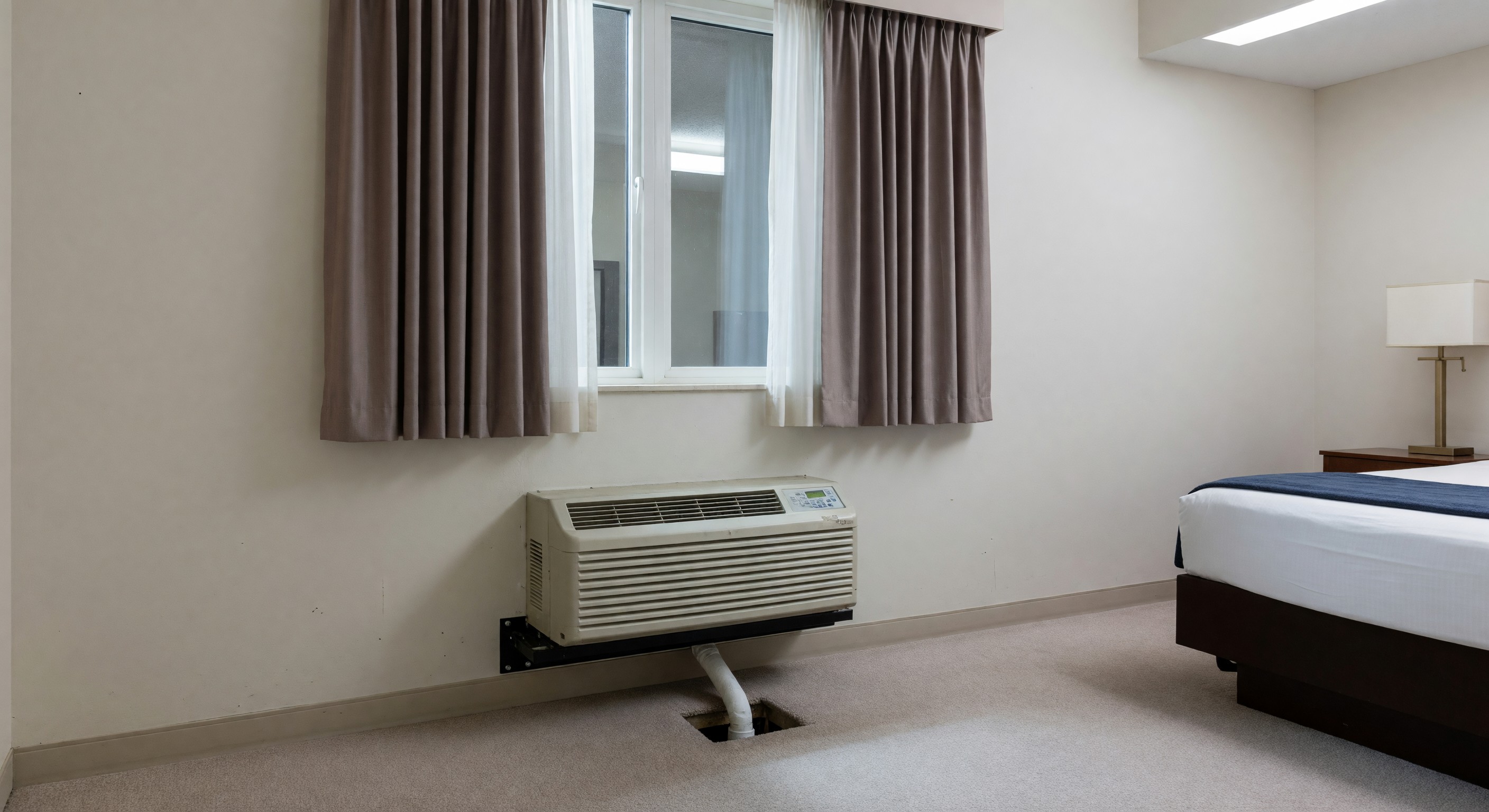 Hotel room with PTAC unit under window showing typical installation